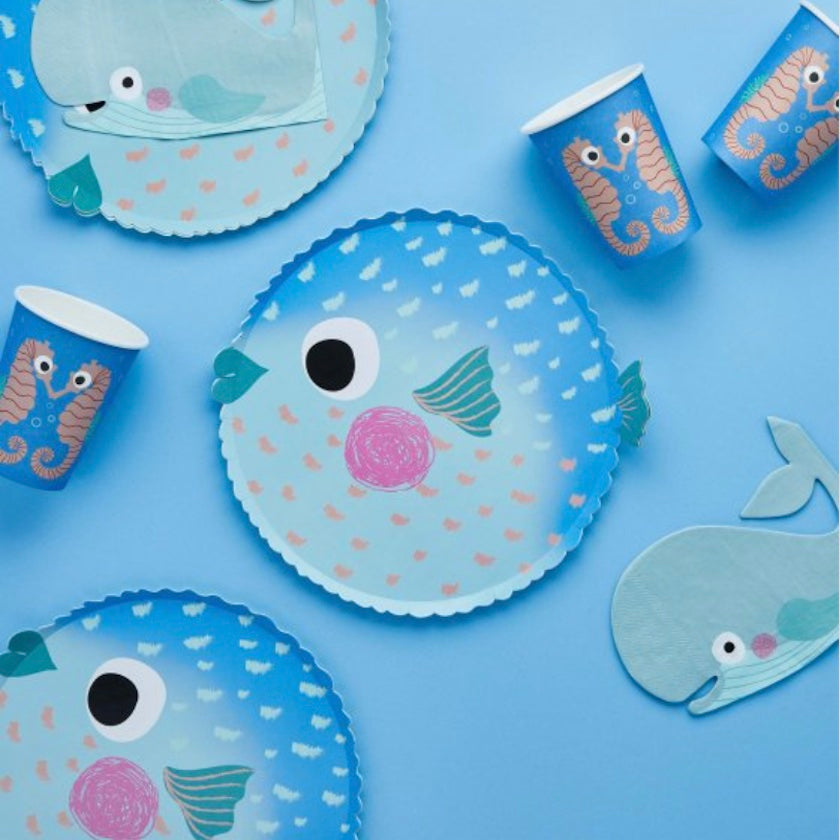 Children's party tableware with fish and seahorse designs on a blue background