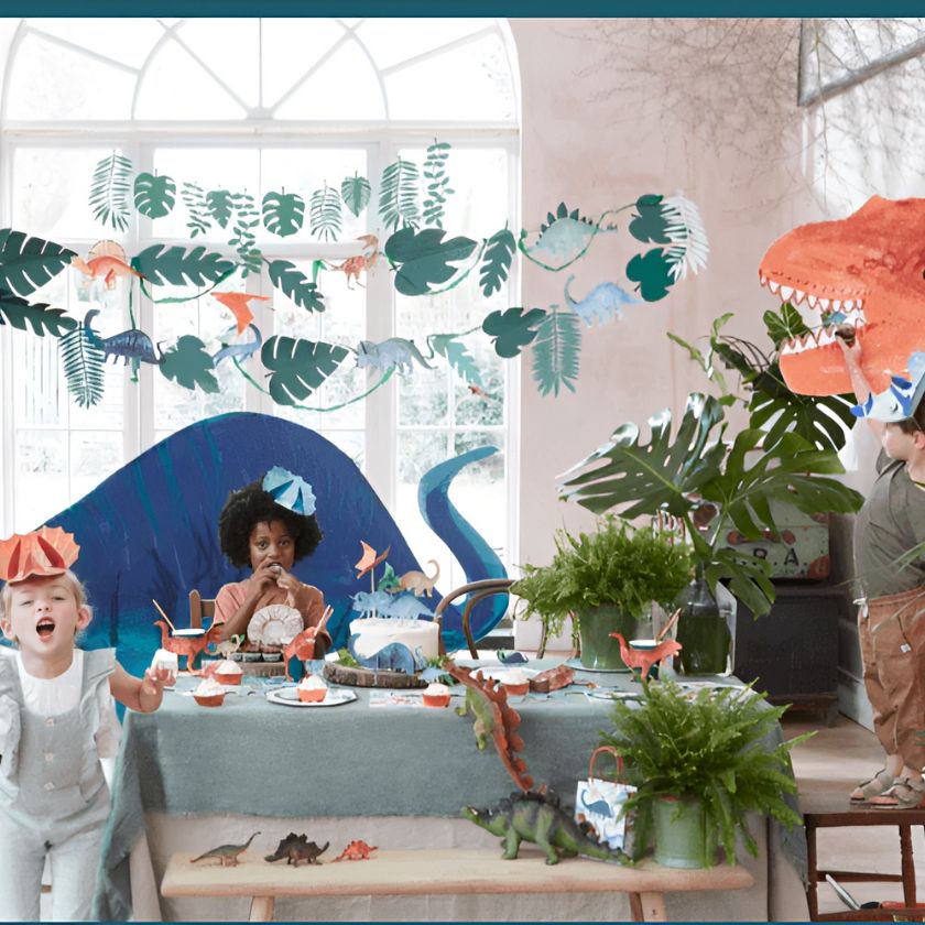 Party scene includes image of kids with dinosaur hats, dinosaur kingdom garland hung up, dinosaur plates on table and giant dinosaur cut outs