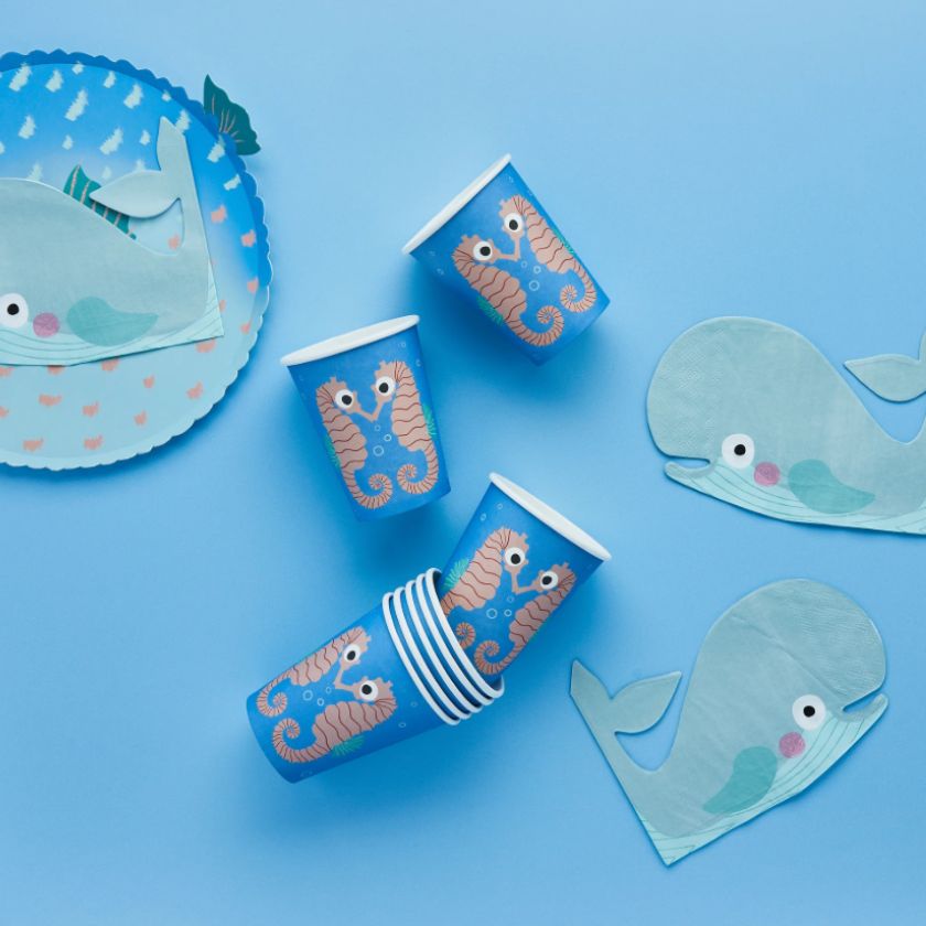 Party supplies with whale and seahorse designs on a blue background
