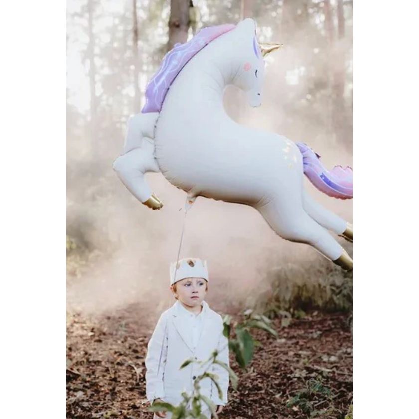 Boy at party holding giant unicorn balloon above