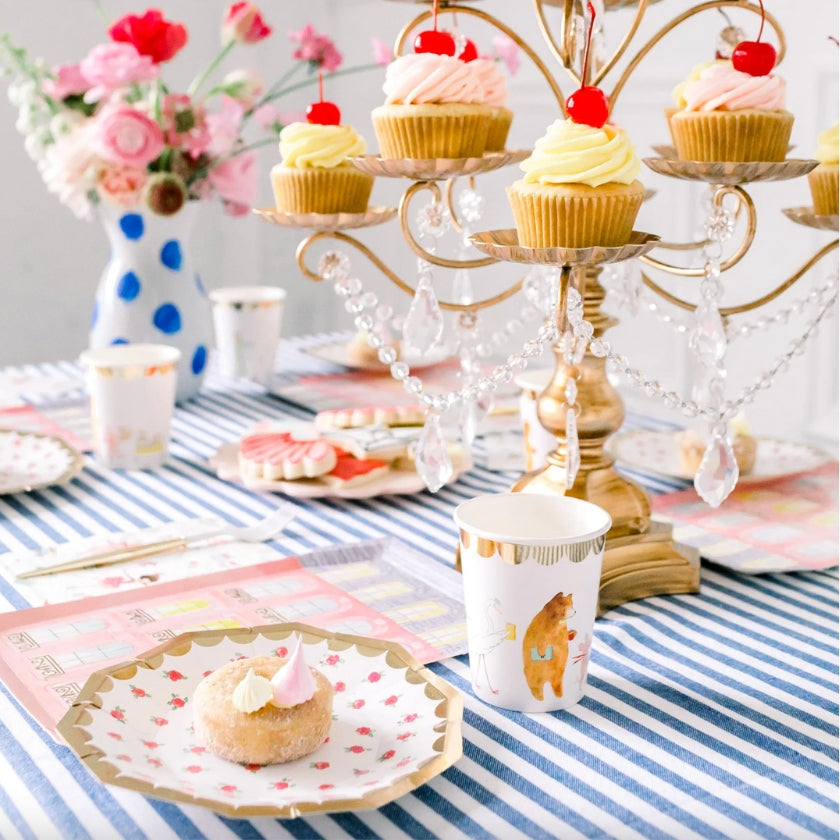 Table setting with candelabra, blue stripe tablecloth, tea rose plates and cupcakes