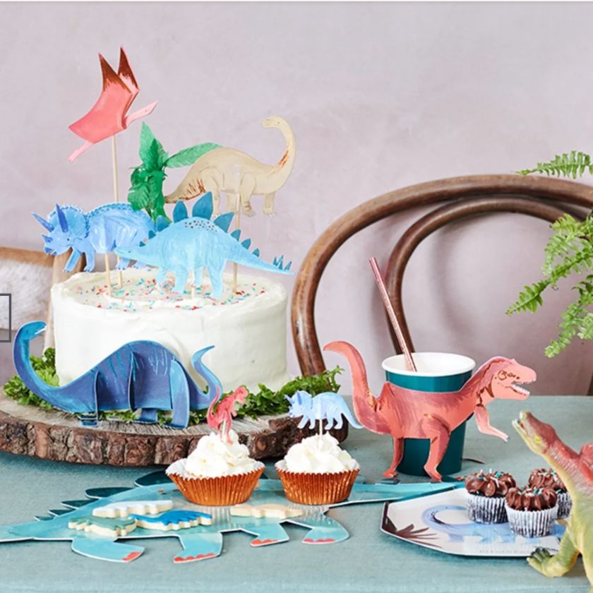 Great photo of Meri Meri Dinosaur party supplies on table including dinosaur cake toppers, plates, cups and platters.