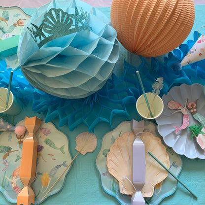 Gorgeous table setting for a mermaid party including mermaid plates, mermaid cake toppers and mermaid crowns