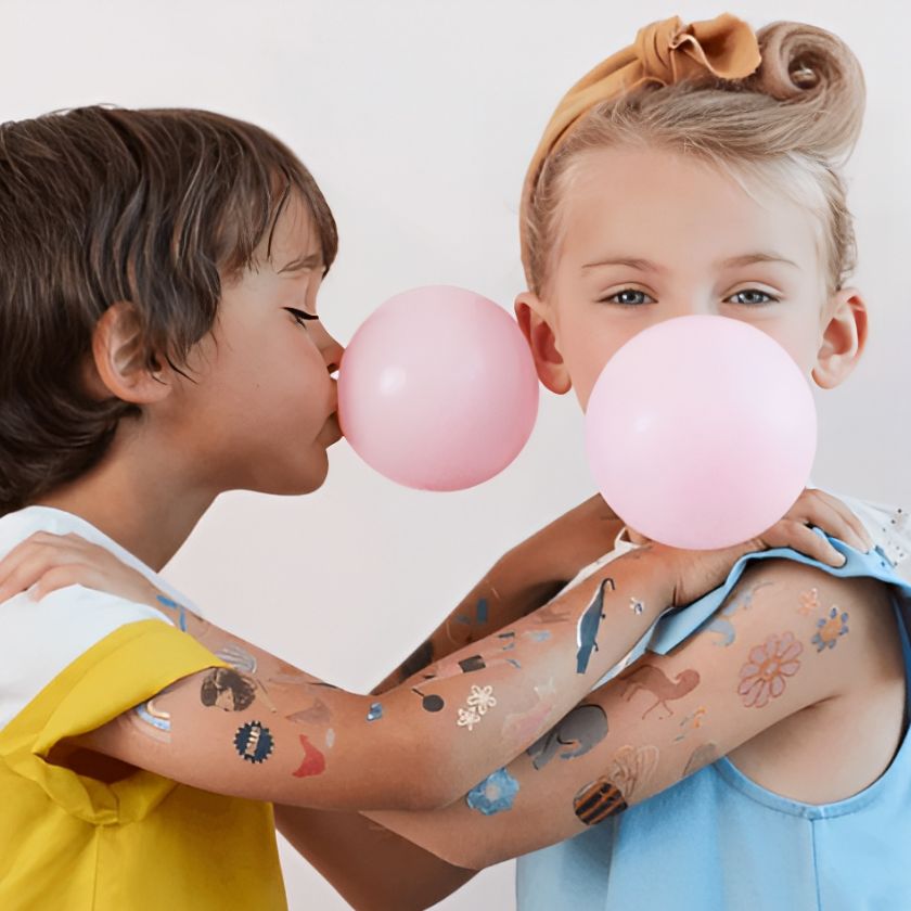 2 Children delightfully playing with Mermaid Tattoos on arms and with balloons