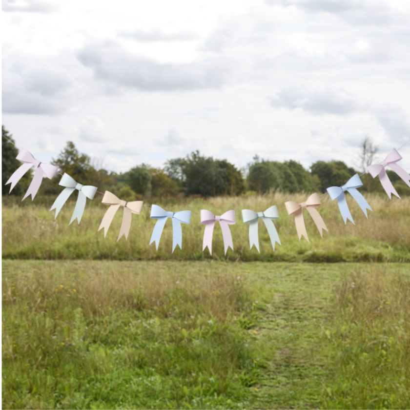 String of colorful bows in a grassy field with trees in the background