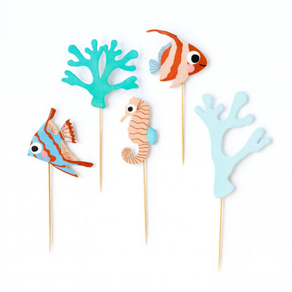 Set of ocean-themed cake toppers including fish, seahorse, and coral on wooden picks